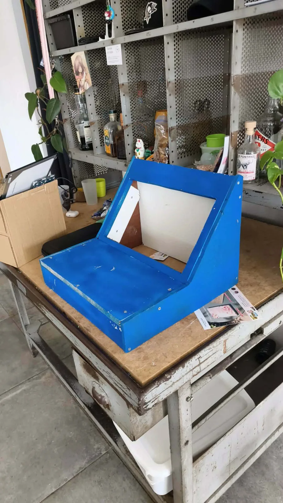 Les pièces en bois de la borne, peintes en bleu et posées sur une bâche